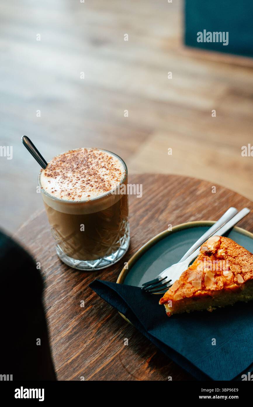 Enjoying dirty chai with oat milk and almond cake at a cozy cafe Stock Photo