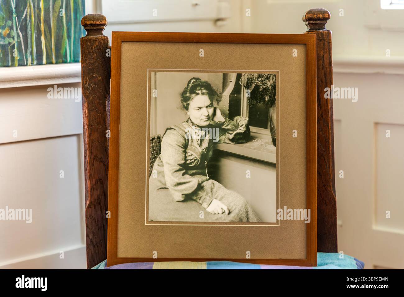 A framed reproduction in the Mia and Hermann Hesse House in Gaienhofen, Baden-Württemberg, Germany, shows Mia Hesse sitting with a serious, sad expression at the window of her house. The exhibition piece stands propped on a chair inside the house. Stock Photo
