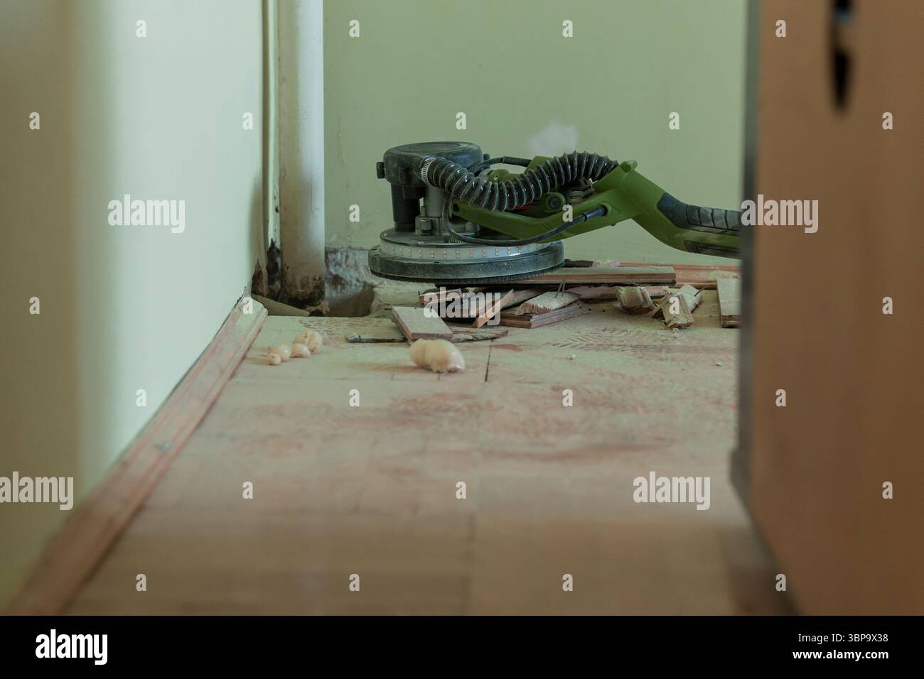 A detailed view of a power floor sander operating on a partially ...