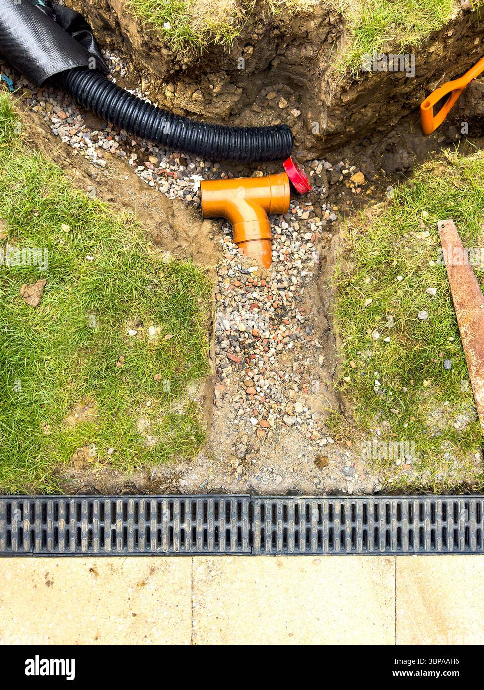 Pipe laying & trenching work in progress on a grassy lawn for field drain drainage installation and landscaping project new build housing problems - Smartphone Captured Stock Image
