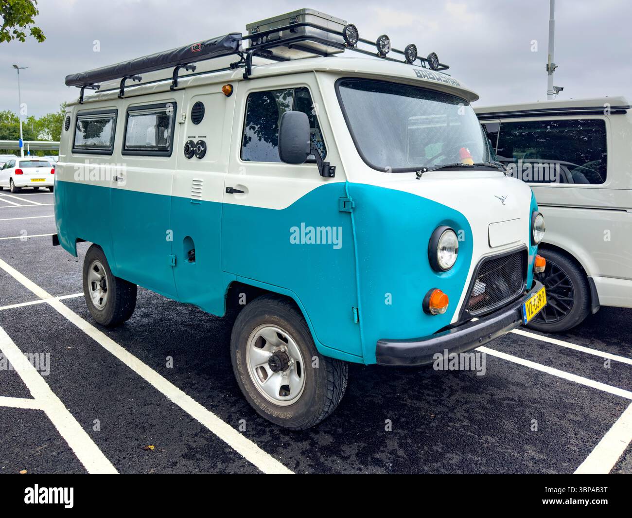 Vintage blue and white Soviet-era UAZ 452 camper van parked in a lot, showcasing classic design and robust build - Smartphone Captured Stock Image