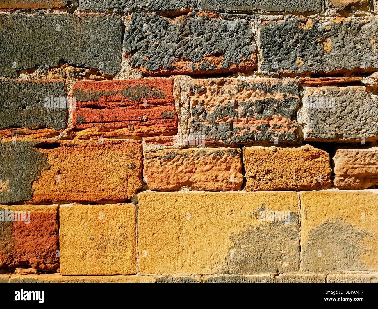 Ancient brick wall in warm yellow-orange sand tones illuminated by sunlight with irregular brick shapes Stock Photo
