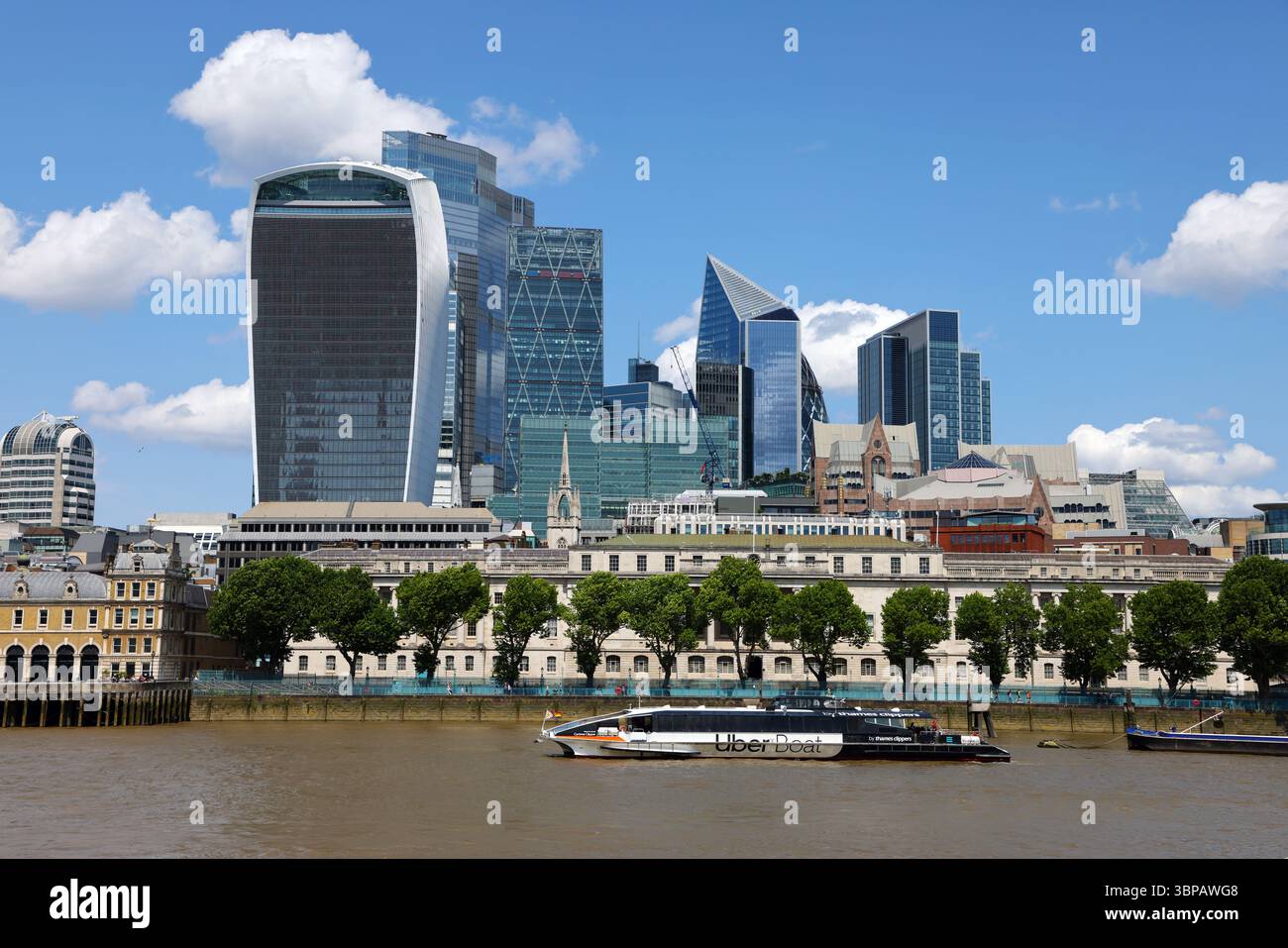 Office blocks of the City of London skyline and Uber Boat on the River Thames, London, England Stock Photo