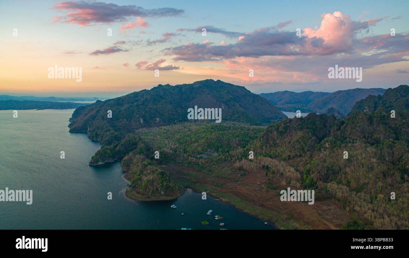Glimmering under golden hour light, the Vajiralongkorn Reservoir reflects the sky’s colors in still, glassy water. The reveals the region’s vastness a Stock Photo