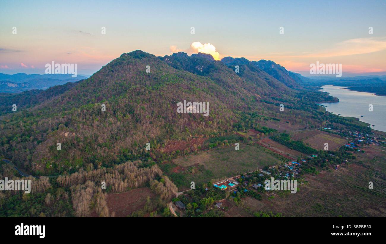 stunning aerial scene captures the meeting point of rugged mountains and endless lake. With vibrant cloudscapes and scattered islands, Vajiralongkorn Stock Photo