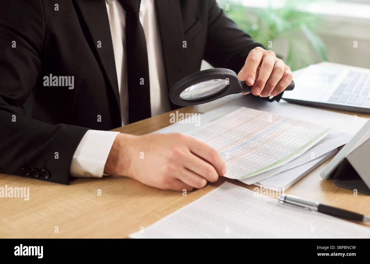 Unrecognizable man dressed formally, using magnifying glass to zoom document Stock Photo