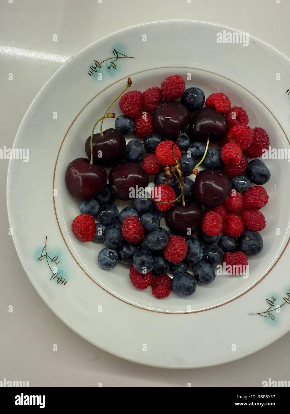 Cherry Vs Raspberry Size This image shows a top-down view of a white ceramic plate containing ...