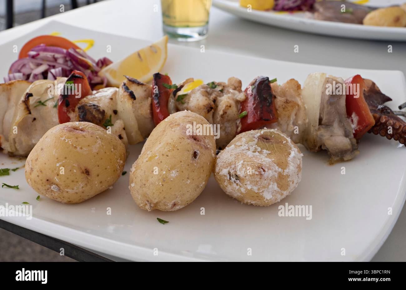 Canarian potatoes and fish brochette in the old harbour El Cotillo, Playa del Muellito, Paseo marítimo, Fuerteventura, Canary Islands, Spain Stock Photo