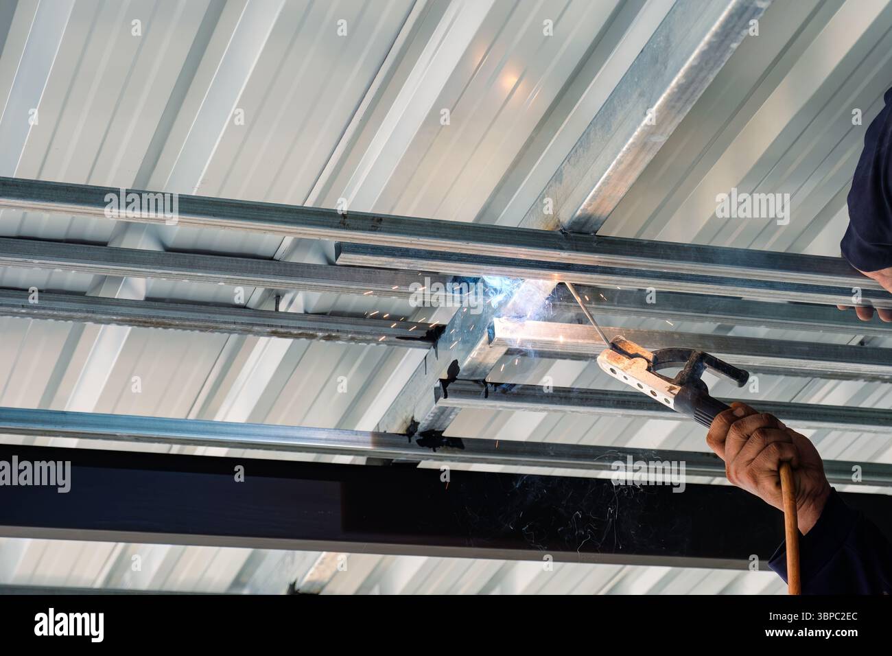 Construction worker installing and welding with flying sparks on steel ...