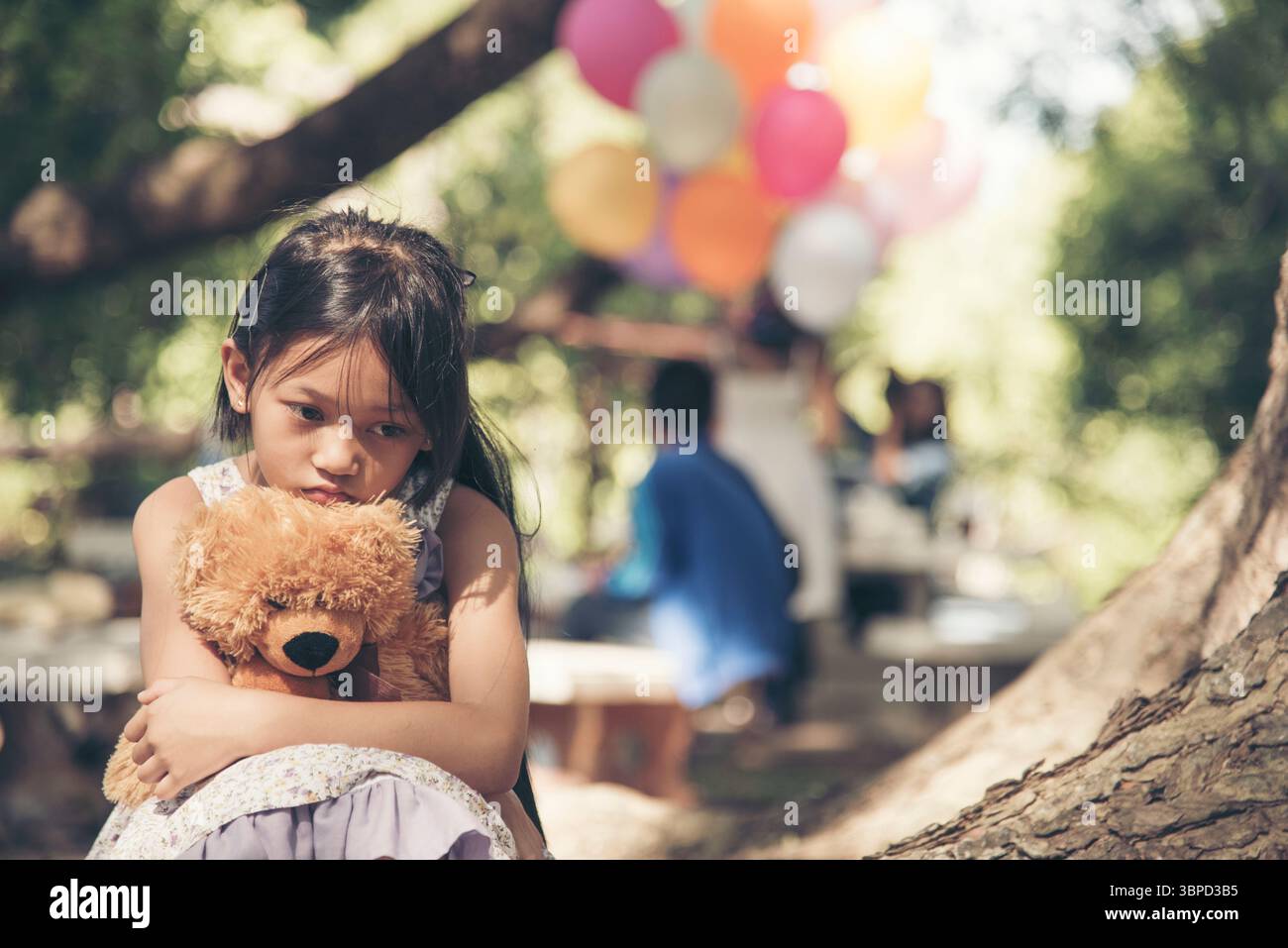 Sad girl hugging teddy bear sadness alone in green garden park. Lonely girl feeling sad unhappy sitting outdoors with best friend toy. Autism child pl Stock Photo