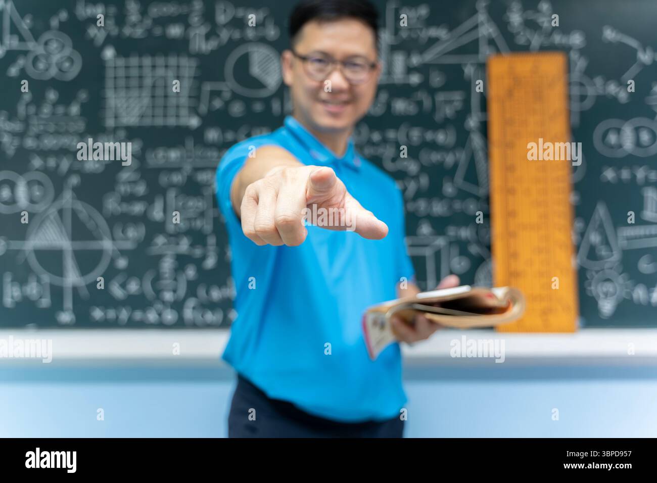 Asian male mathematics teacher in blue shirt smiling and pointing ...