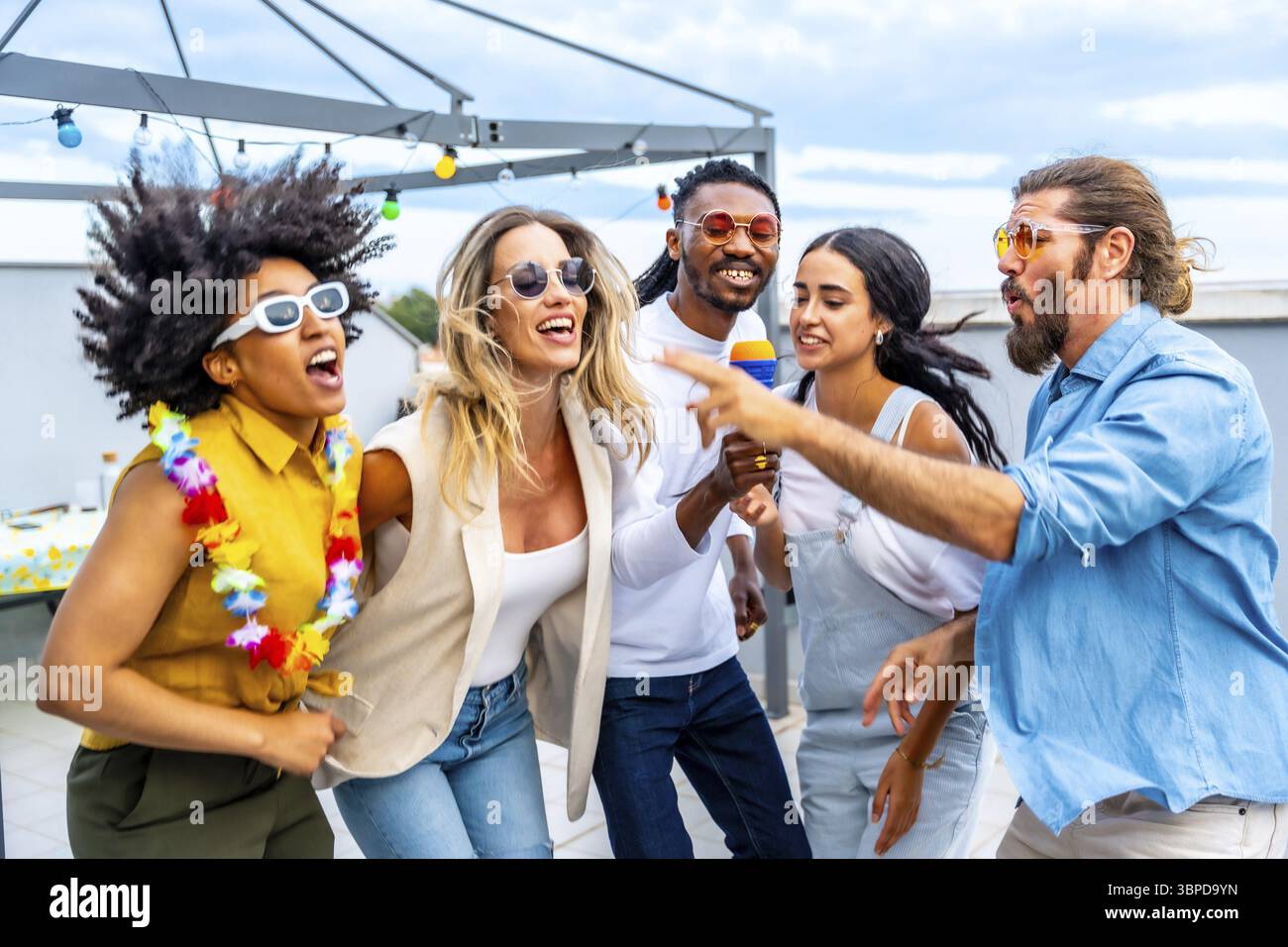 Cheerful multi ethnic friends enjoying a vibrant rooftop party, singing ...
