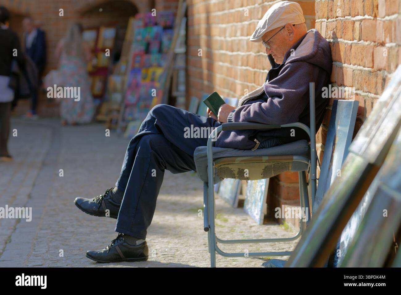 Old man selling his paints near a brick wall from the old town Stock Photo