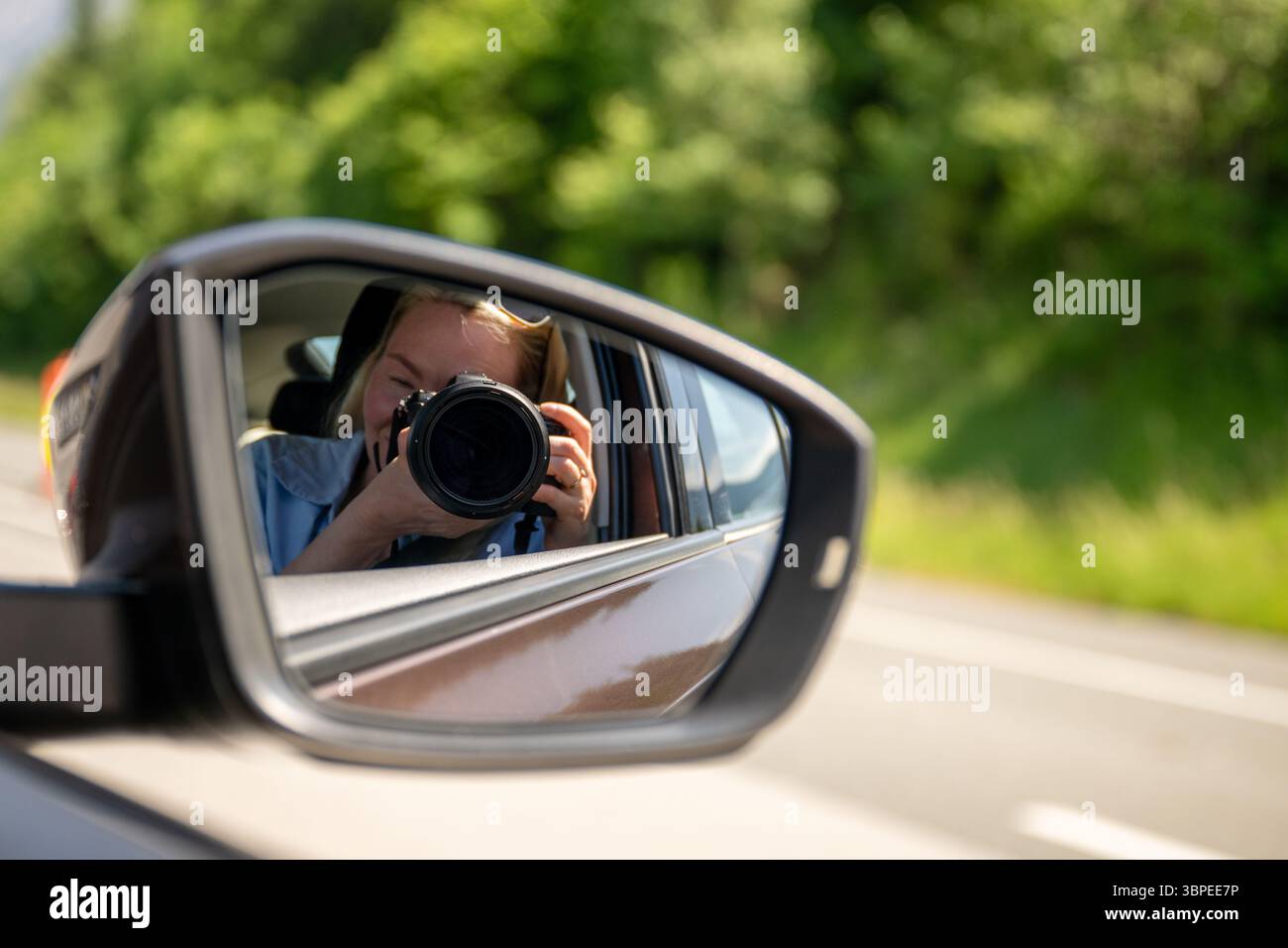 Photographer taking picture reflected in car side mirror on sunny day Stock Photo
