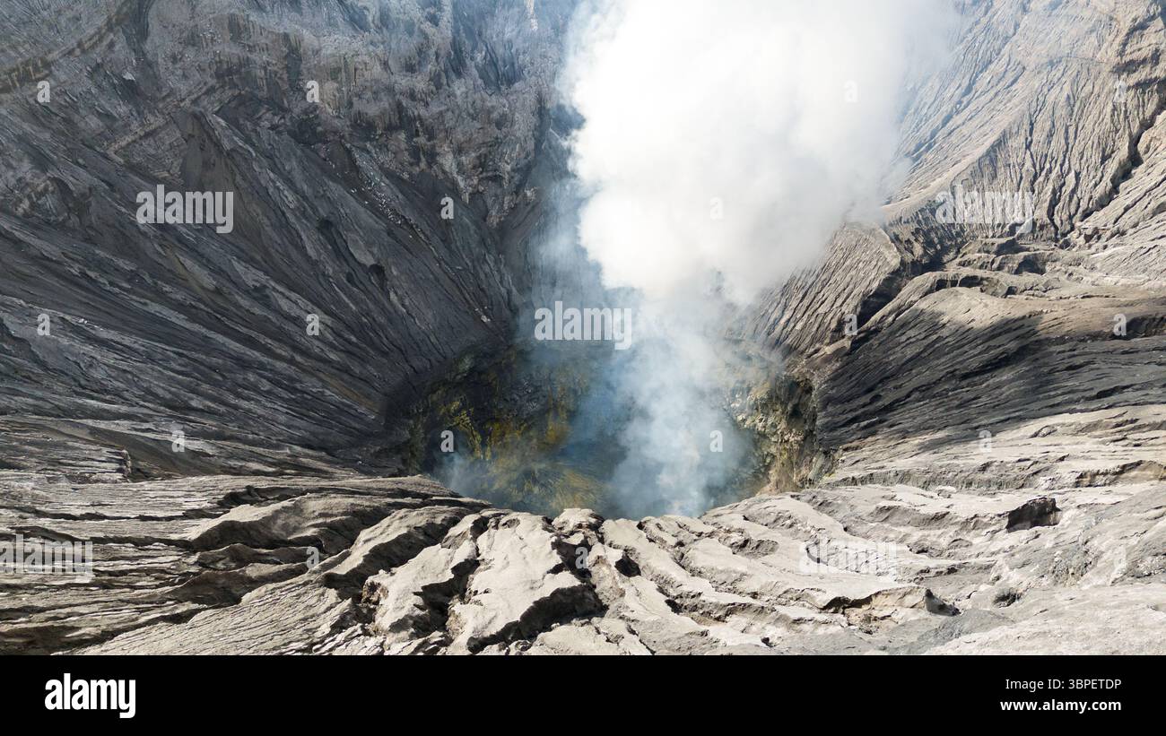 Aerial view of the volcanic crater, with wisps of smoke rising from its ...