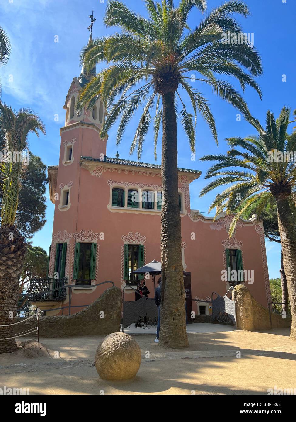 The stunning pink building at Park Güell with palm trees and blue sky. Barcelona Spain - Smartphone Captured Stock Image