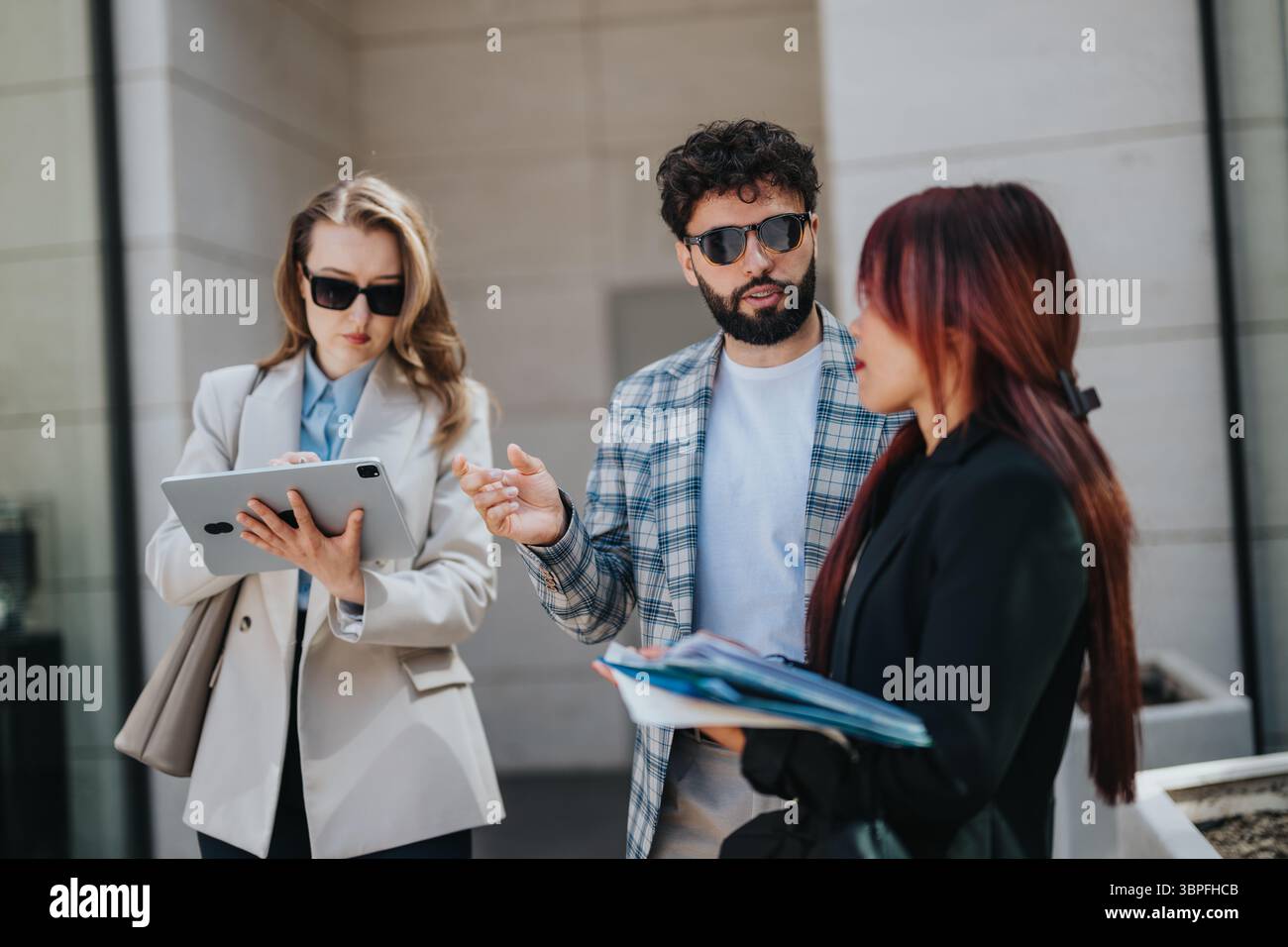 Group of diverse professionals collaborating outdoors using technology and documents Stock Photo
