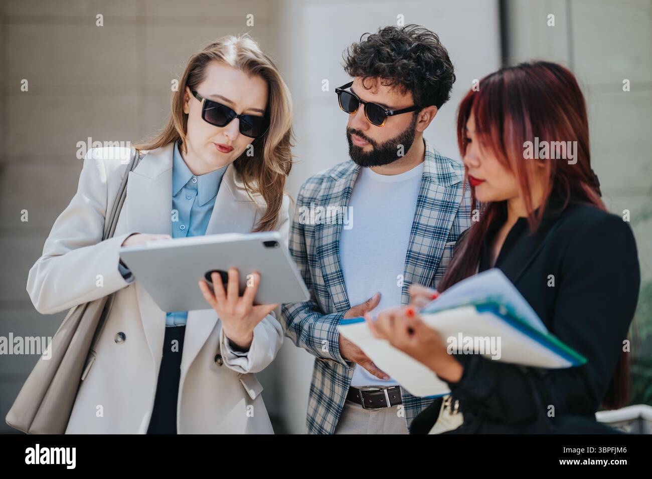 Colleagues collaborating outdoors using digital tablet and taking professional notes Stock Photo