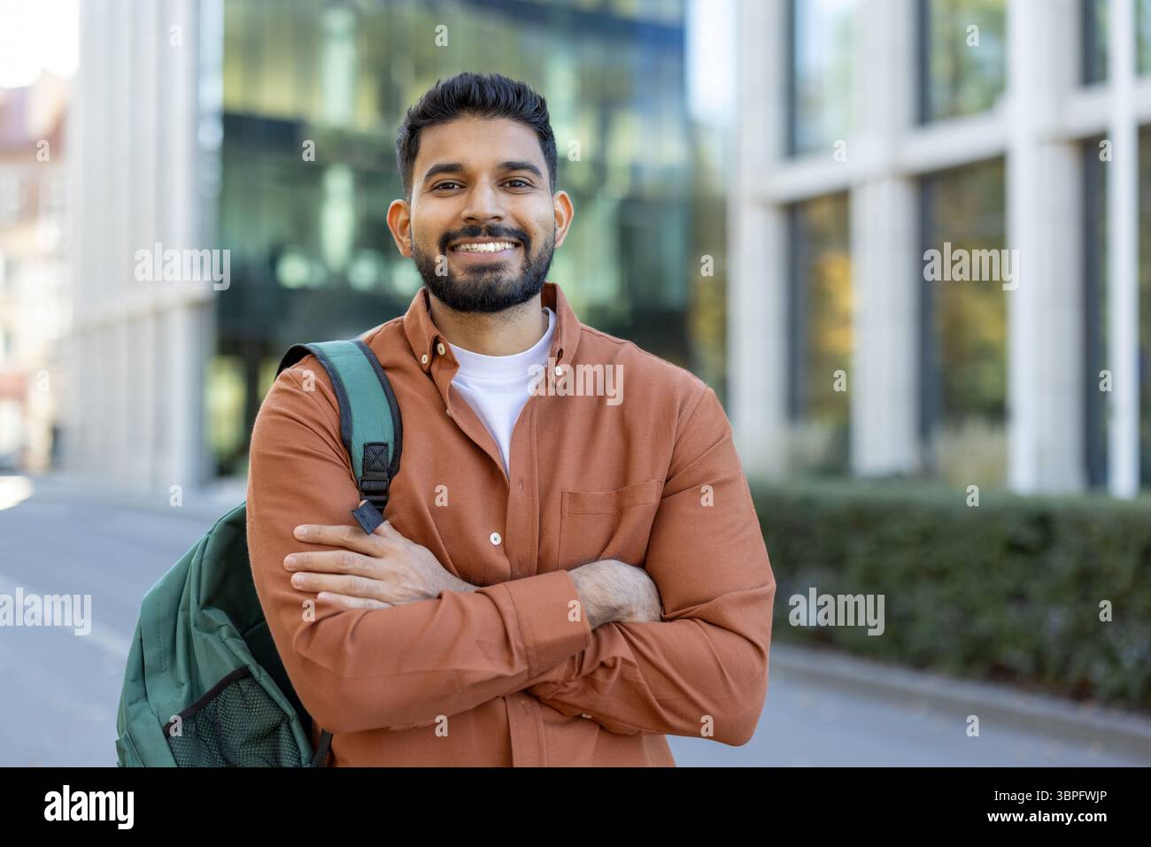 A smiling Indian student with a backpack stands confidently outside a ...