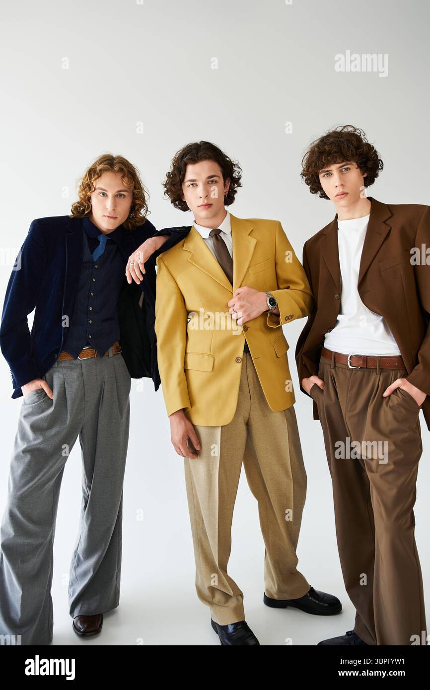 Three young men display their unique styles in a modern studio setting. Stock Photo
