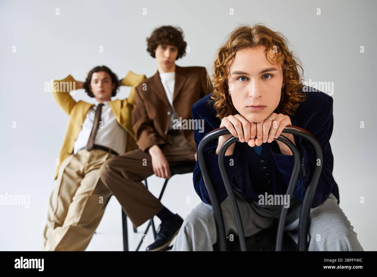 Three young men display their unique styles while posing confidently in a chic studio. Stock Photo