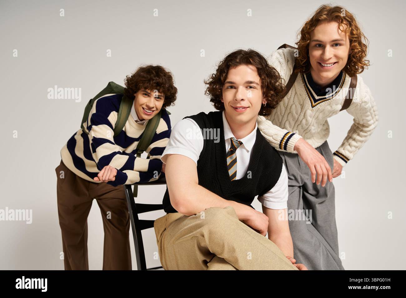 Three fashionable young men display their unique styles while posing playfully in a cozy space. Stock Photo