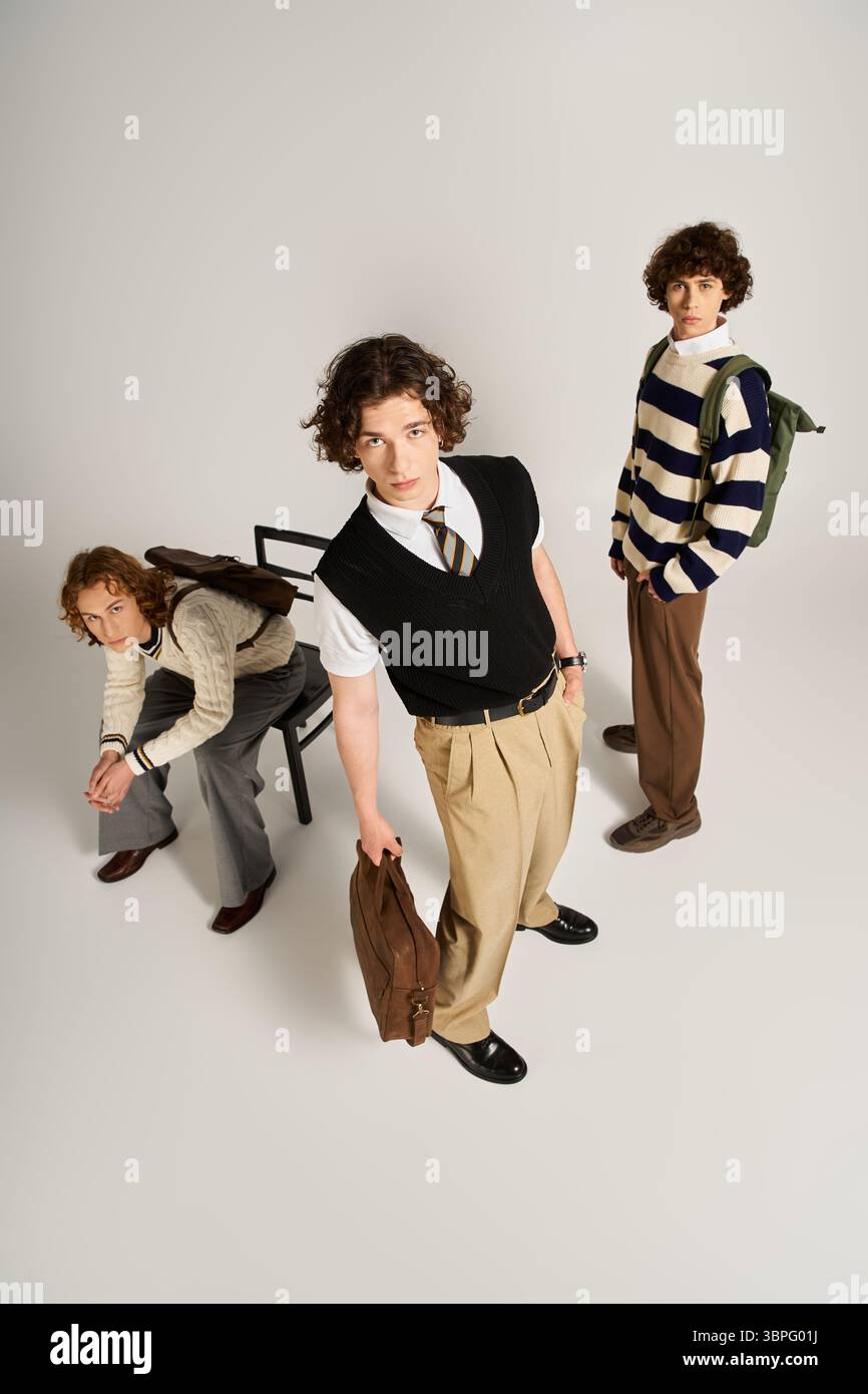 Three young men display their unique fashion sense while posing creatively in a studio. Stock Photo