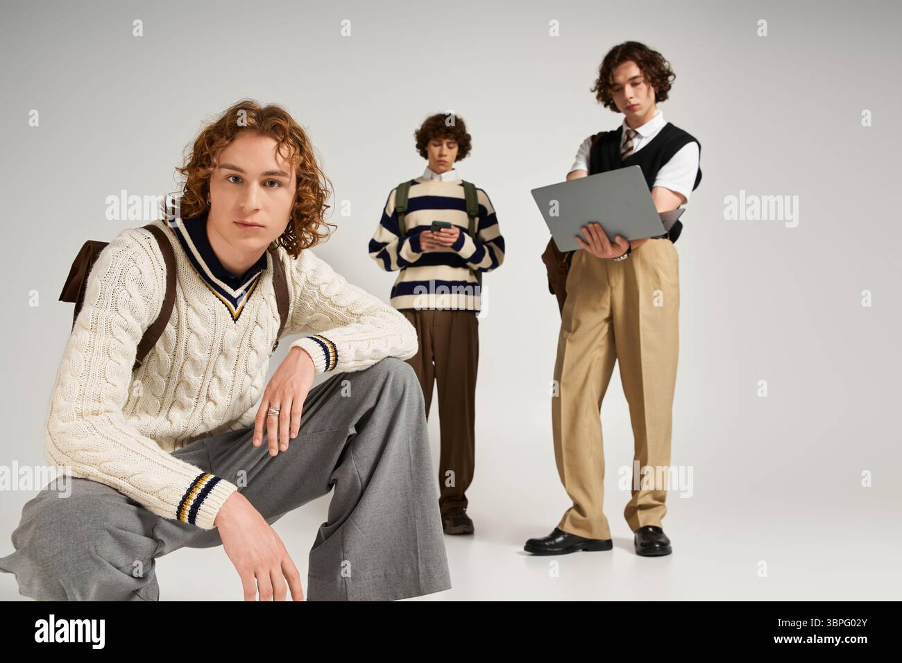 Three young men display their unique styles while enjoying a shared creative vibe in a studio. Stock Photo