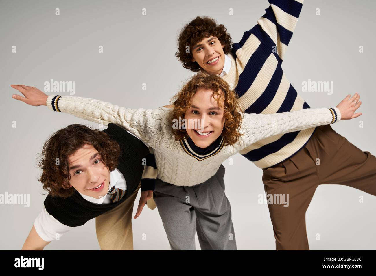 Three young men display unique styles together, exuding confidence in a creative indoor space. Stock Photo