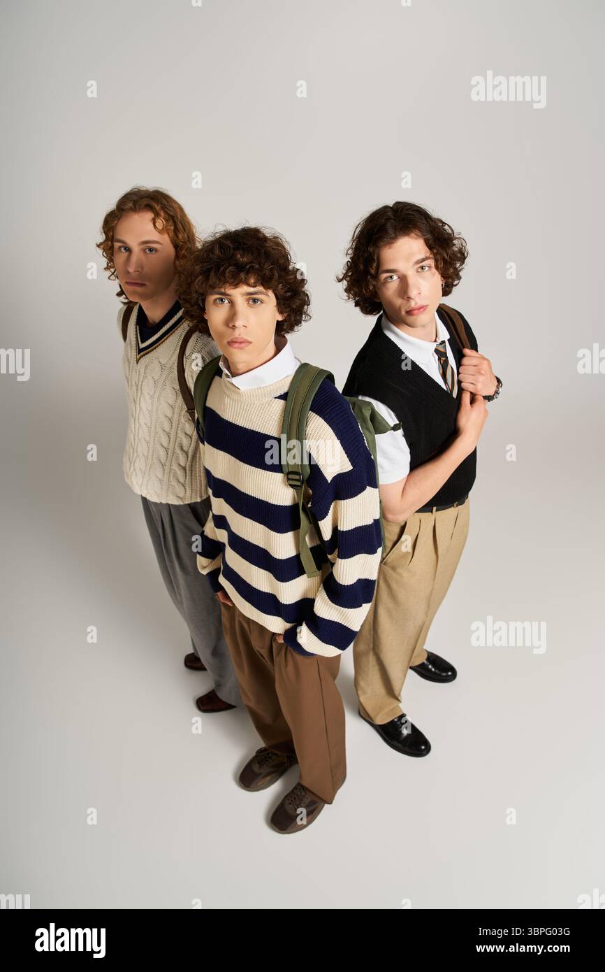 Three friends display their unique styles while posing together against a neutral backdrop. Stock Photo