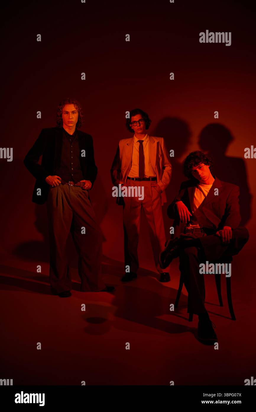 Three young men display their individual styles against a warm, dramatic background. Stock Photo