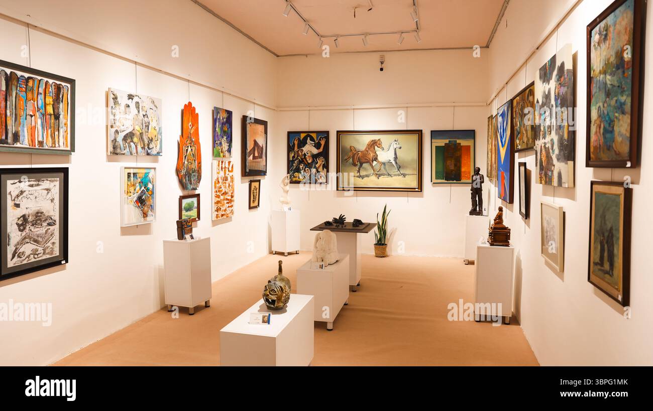 Visitors explore a spacious gallery in Hilla Museum, admiring various contemporary artworks from local artists and cultural themes. Stock Photo