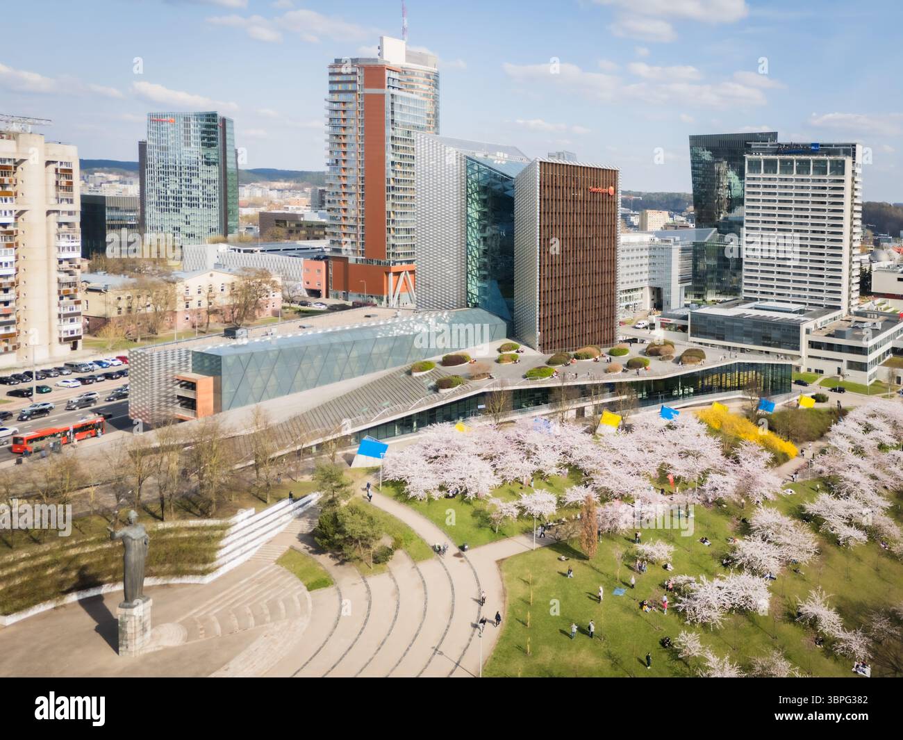Aerial view of modern buildings contrasting against the historic city park with blossoming trees, creating a vivid cityscape., Vilnius, Vilnius County Stock Photo