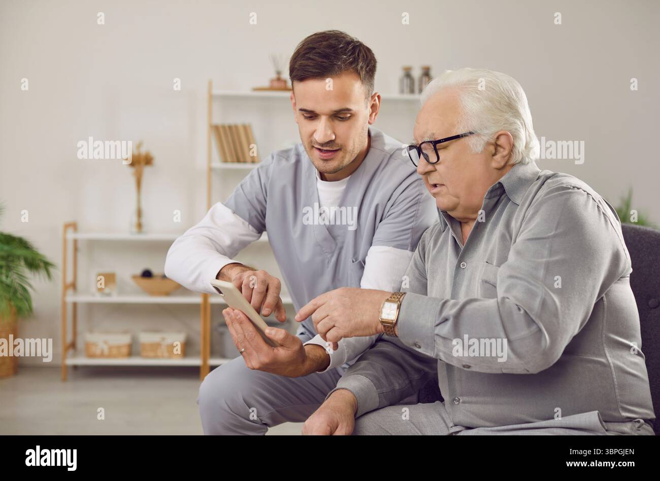 Healthcare professional instructs elderly man on using health app on ...