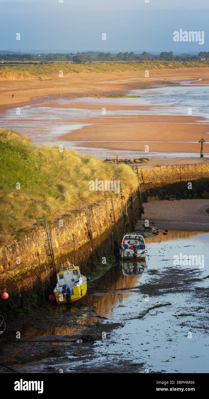 Fishing boats at low tide at the coastal village of Seaton Sluice ...