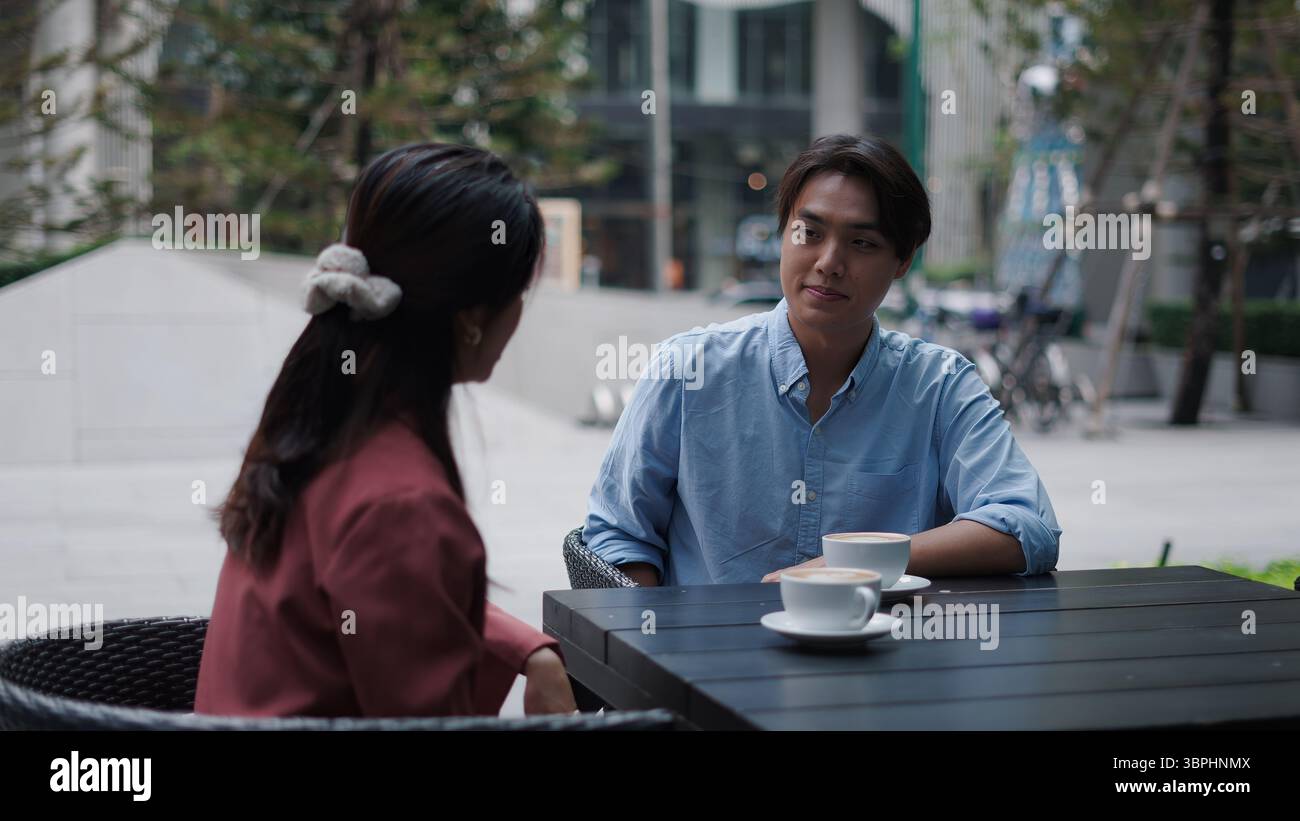 Business colleagues conversing while drinking coffee at outdoor cafe setting Stock Photo