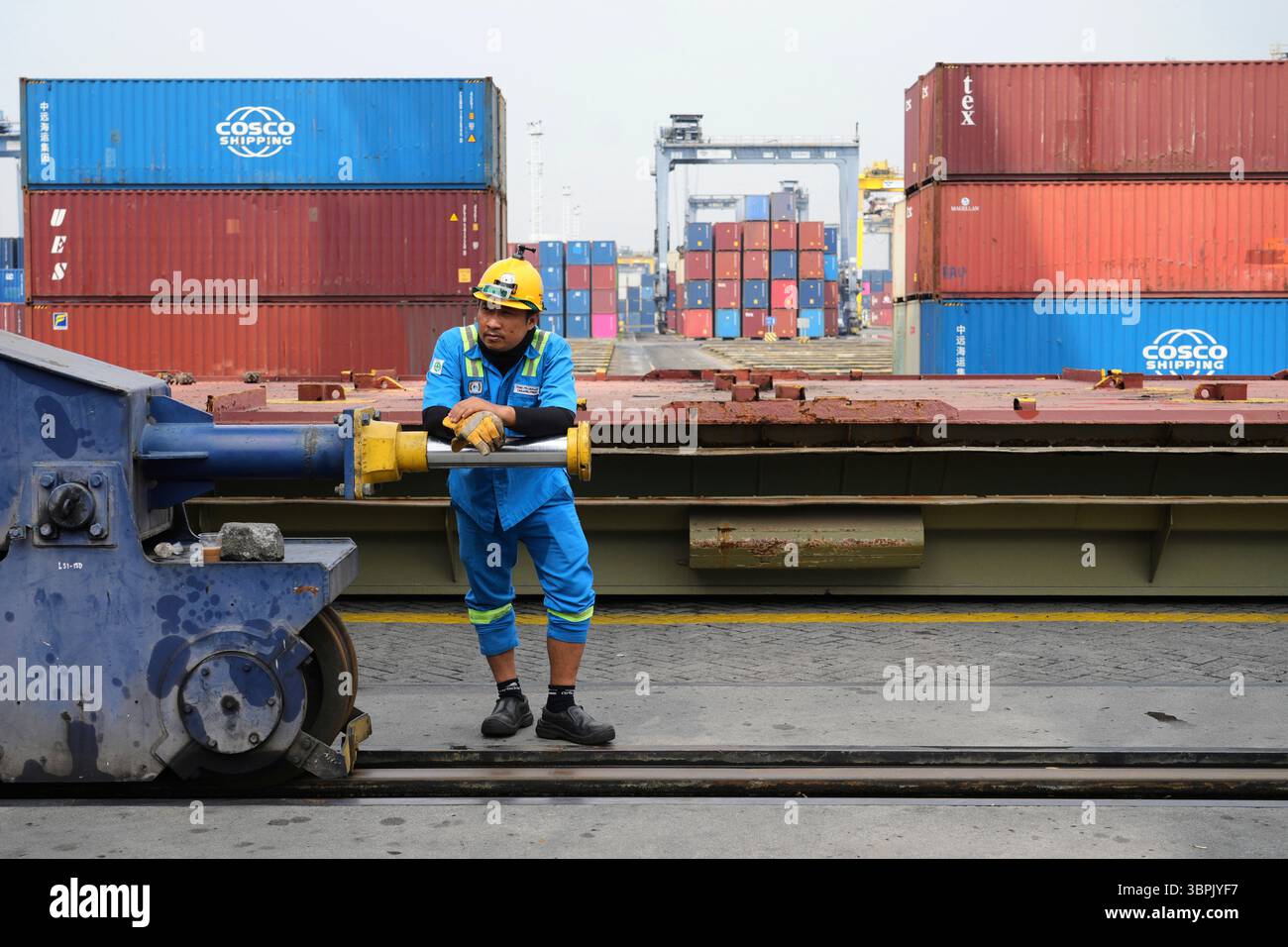 A worker rests during a break as containers are stacked at Jakarta ...