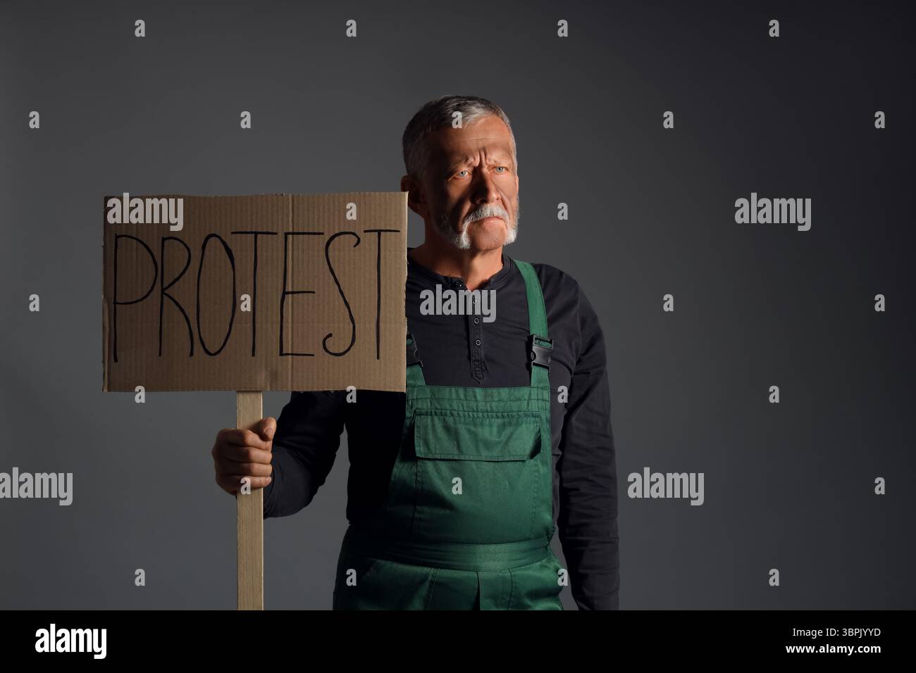 Protesting miner man with placard on dark background Stock Photo