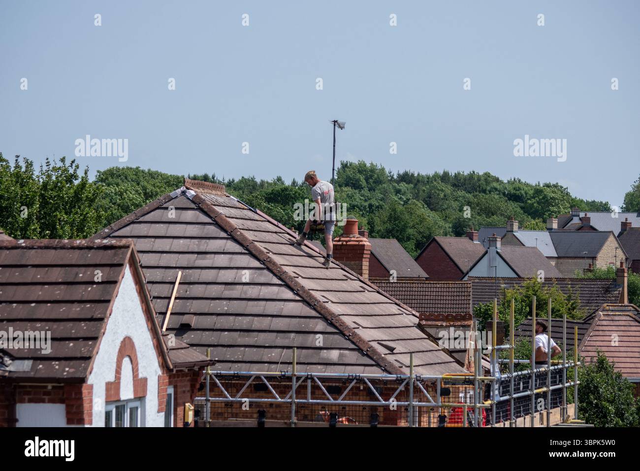Roofers replacing the hip and ridge tiles on a 1990s detached house, Wootton, Northampton, UK Stock Photo