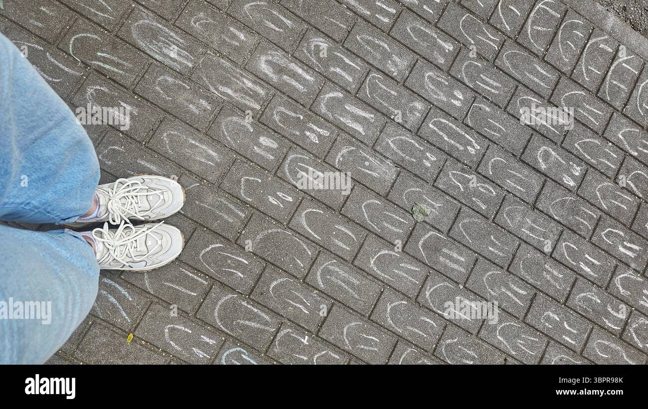 Feet on Chalk‑Drawn Smiles Brick Pavement - Smartphone Captured Stock Image