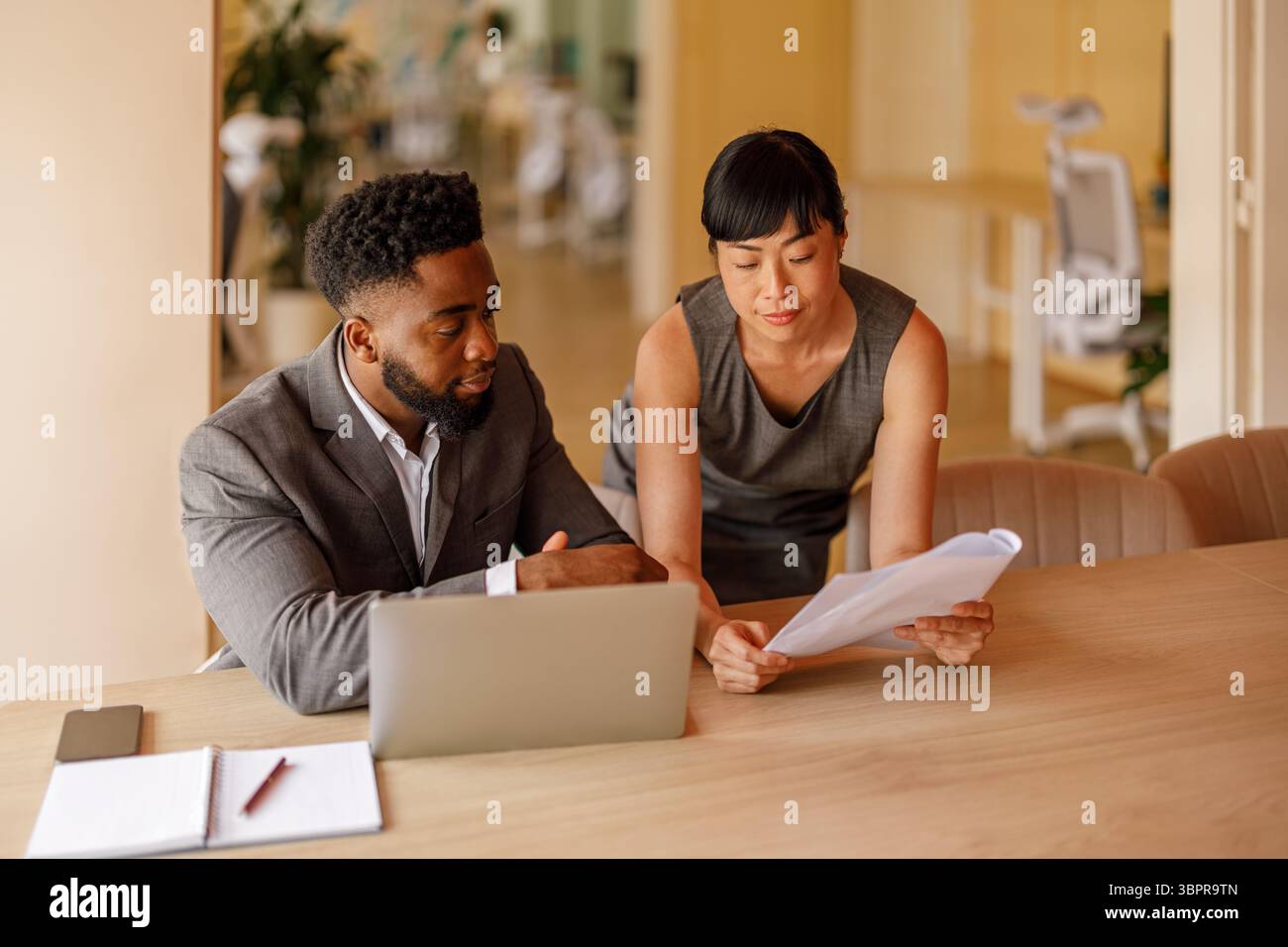 Professional managers analyzing reports using documents and laptop focused on business performance in office Stock Photo