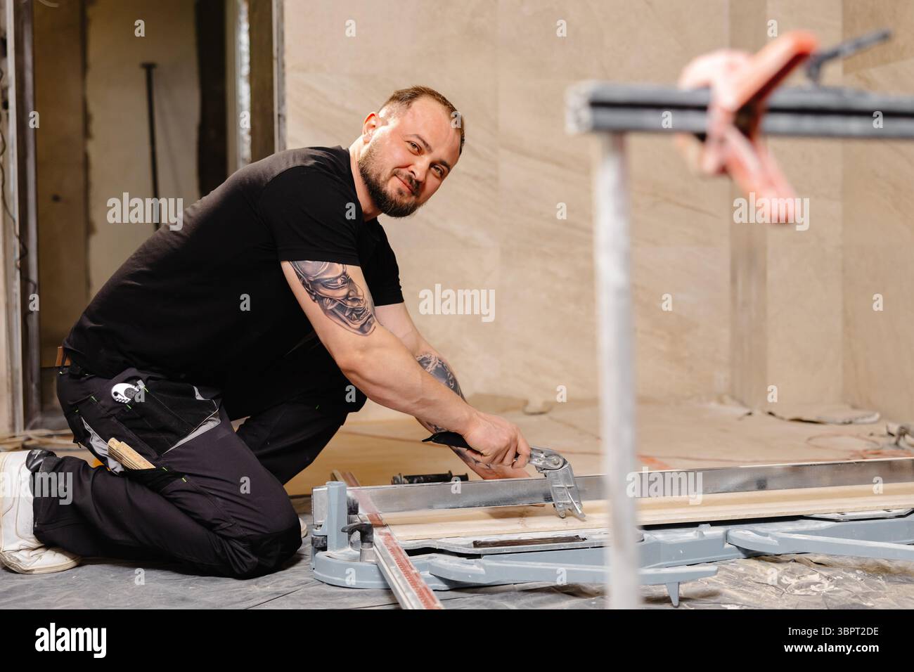 Construction worker cutting ceramic tile using tile cutter while working on bathroom renovation Stock Photo