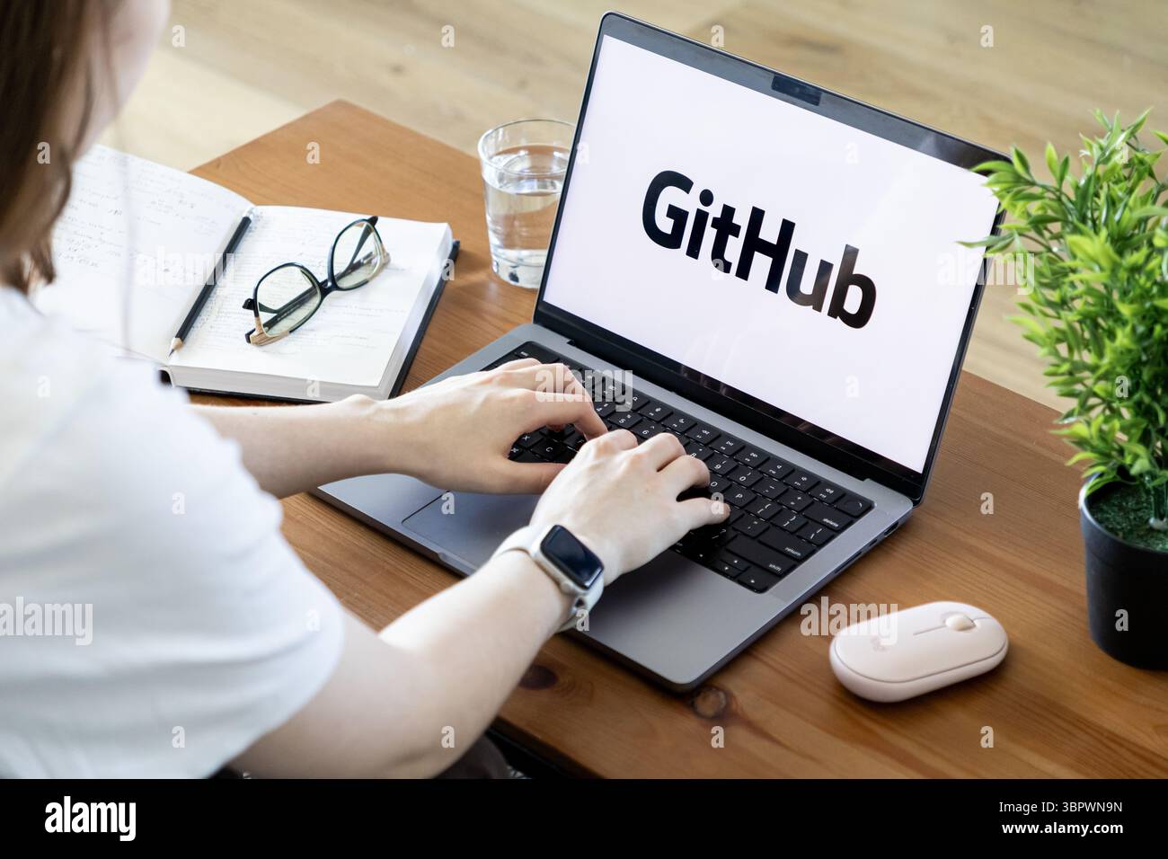Poznan, Poland - June 15, 2025: Hands typing on a laptop showing GitHub, an essential platform for collaborative software development, version control Stock Photo