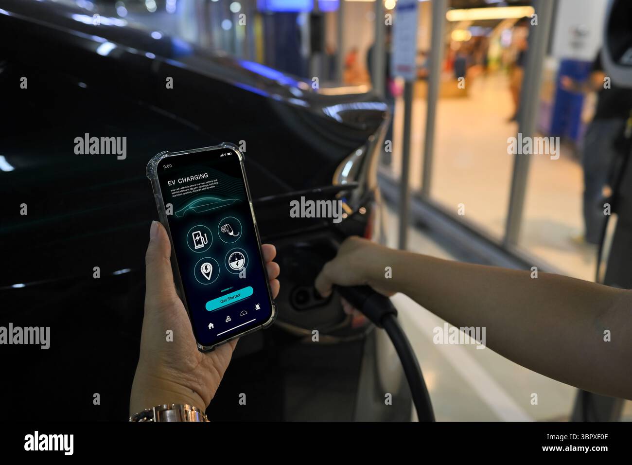 Person holding smartphone with an EV charging app while plugging an ...