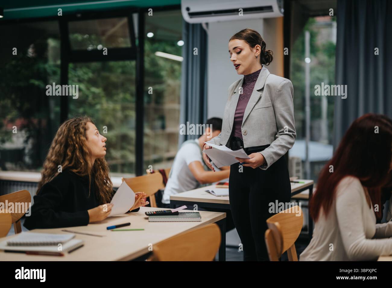 Teacher engaging with attentive students in a modern classroom setting Stock Photo