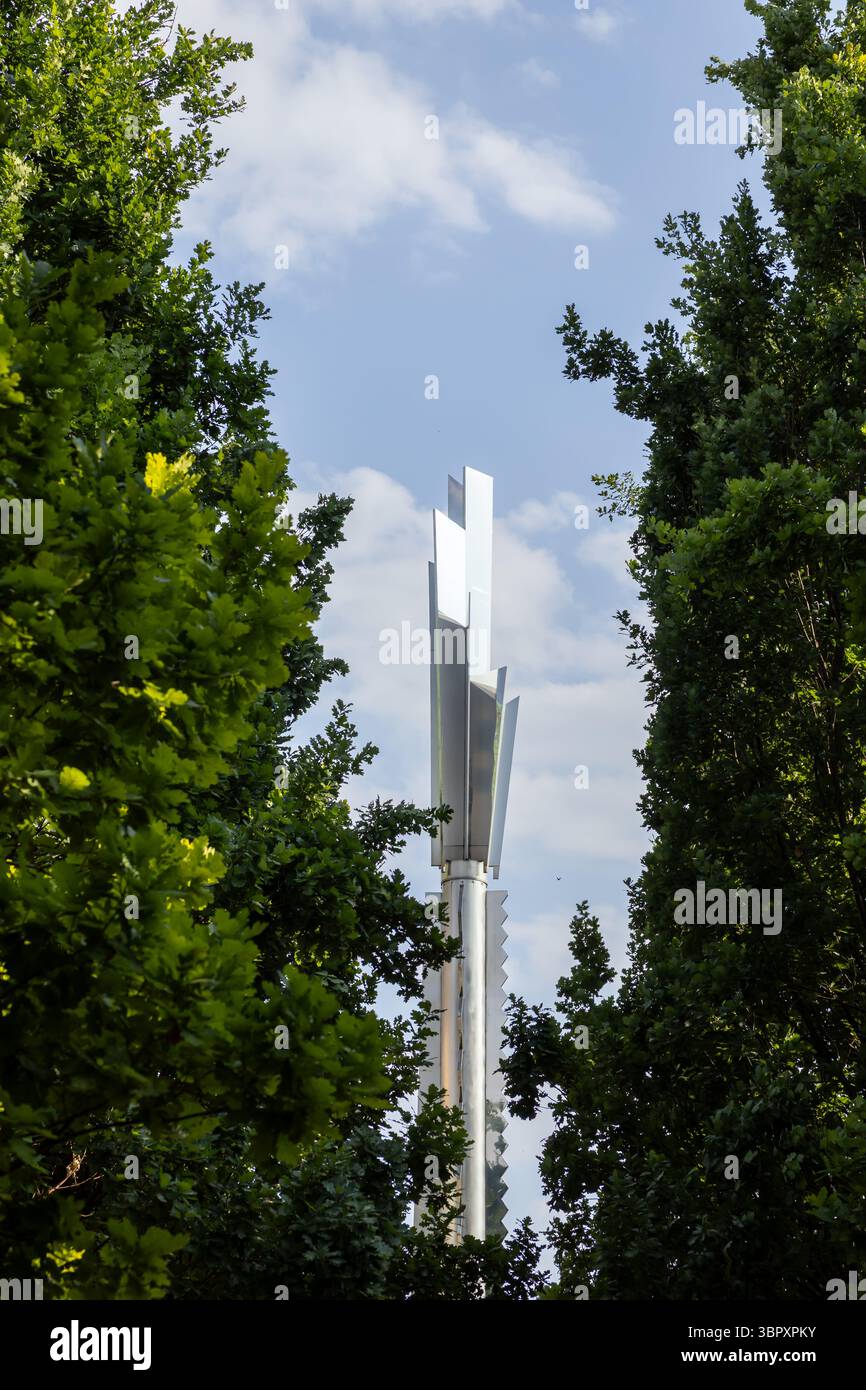 Poznan, Poland - June 18, 2025: A tall metal Stela Heinza Macka sculpture with geometric shape, between green trees and blue sky, for urban art and de Stock Photo