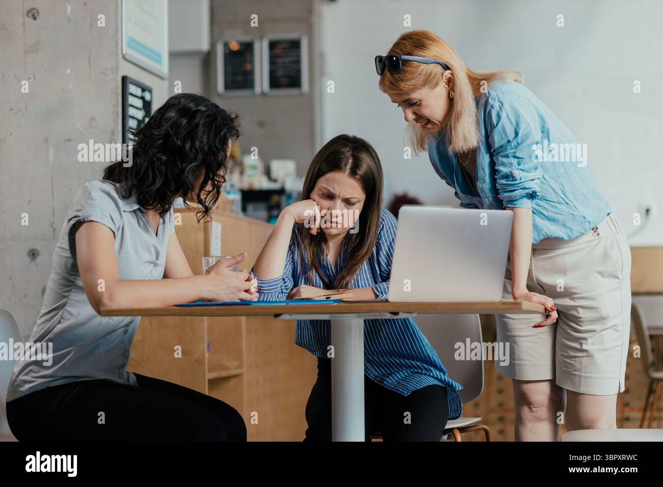 Three female colleagues reviewing meeting notes and feedback in bright ...