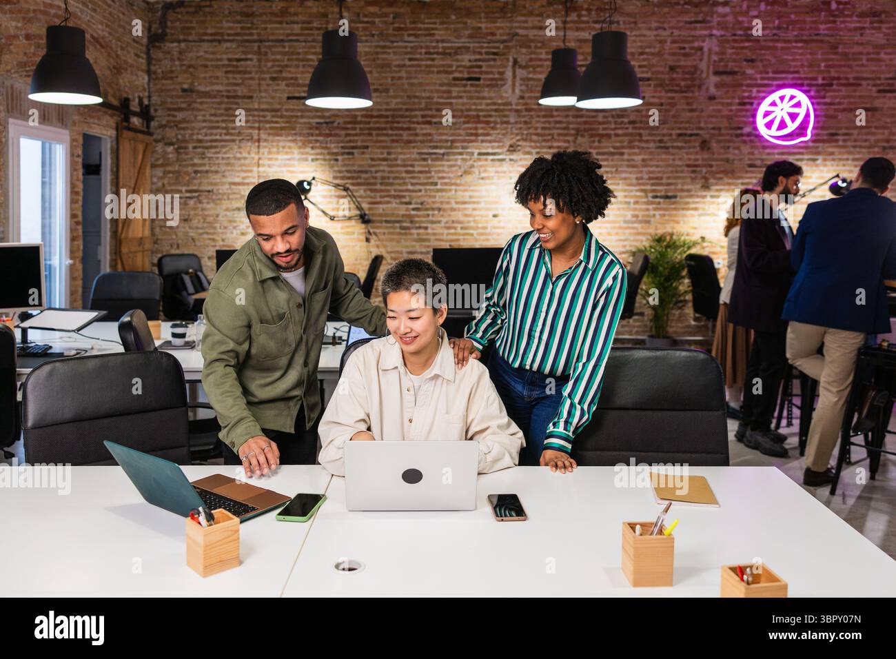 Multi ethnic team collaborating on laptop in modern office Stock Photo