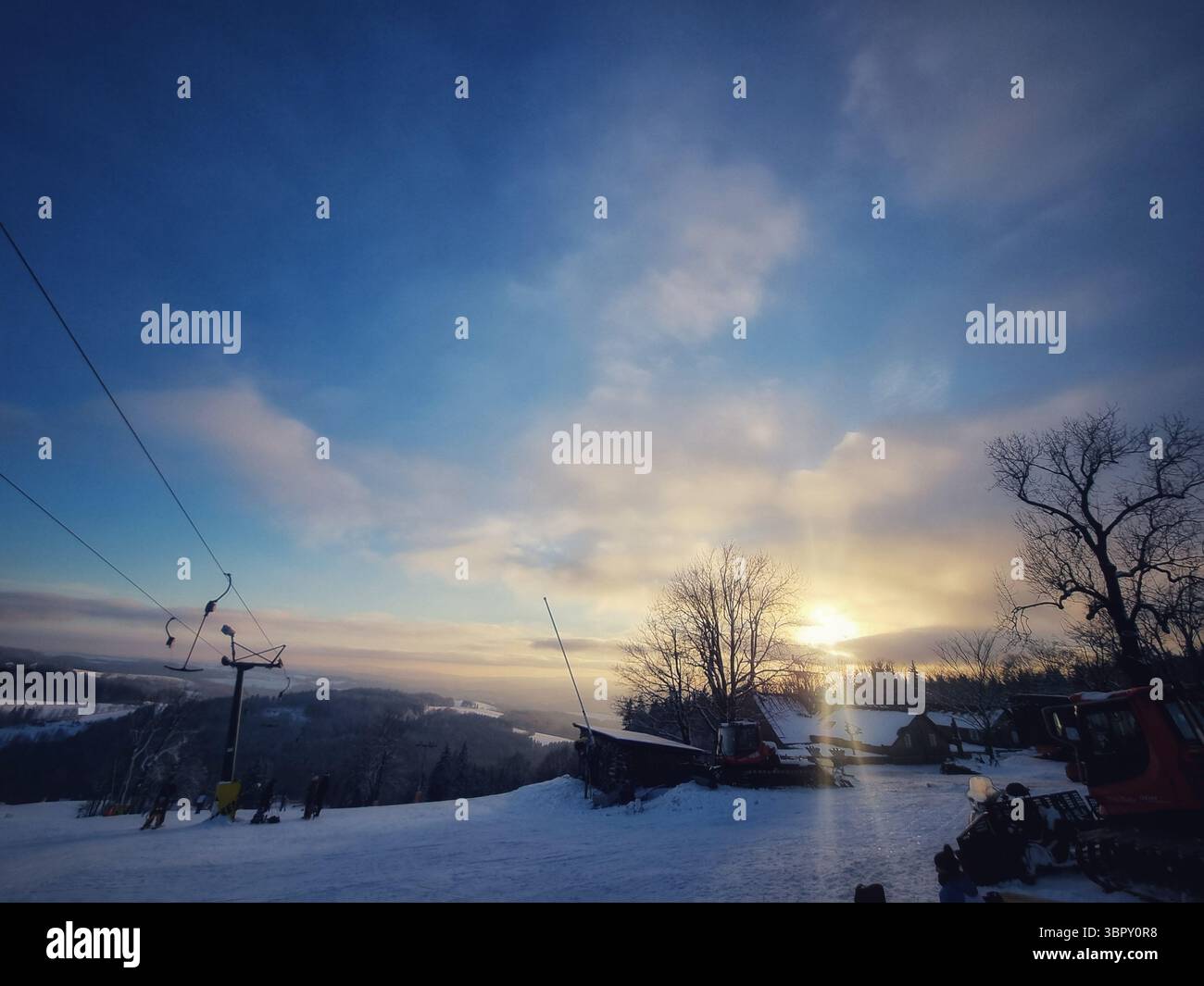 Ski lift and silhouetted trees stand against a colorful twilight sky at a quiet mountain resort, capturing the serene mood after a lovely winter's day. - Smartphone Captured Stock Image