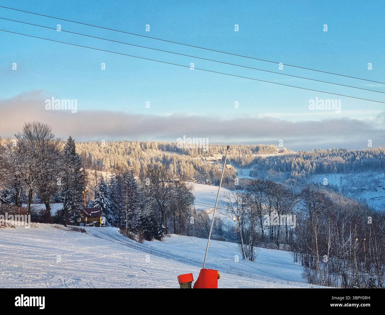 Scenic, wide view of a ski slope through a snowy forest at a Czech mountain resort, under a tranquil winter sky with a beautiful color gradient. - Smartphone Captured Stock Image